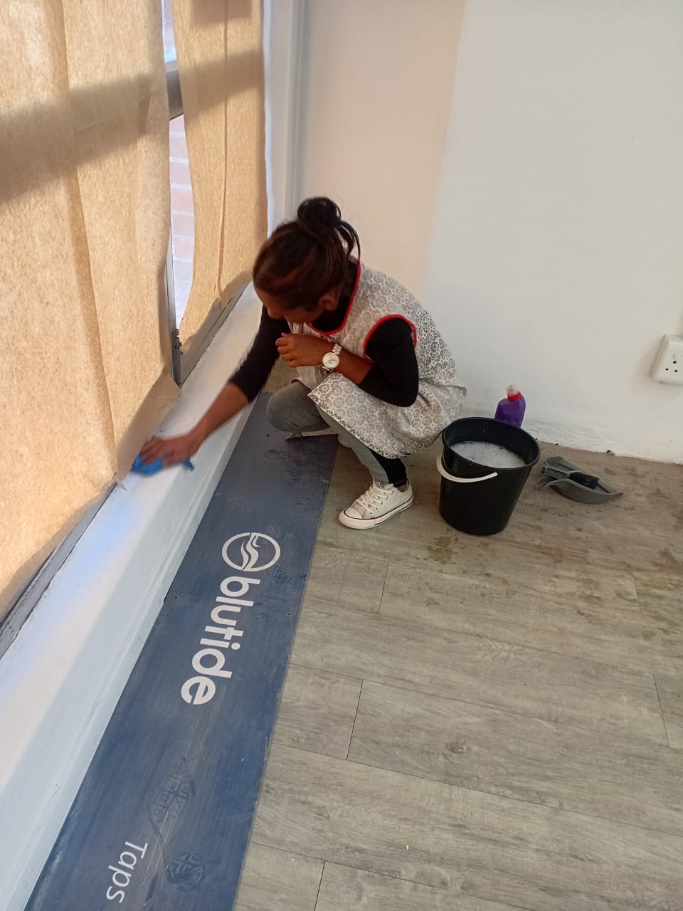 Cleaner washing a window sill with bucket of soapy water